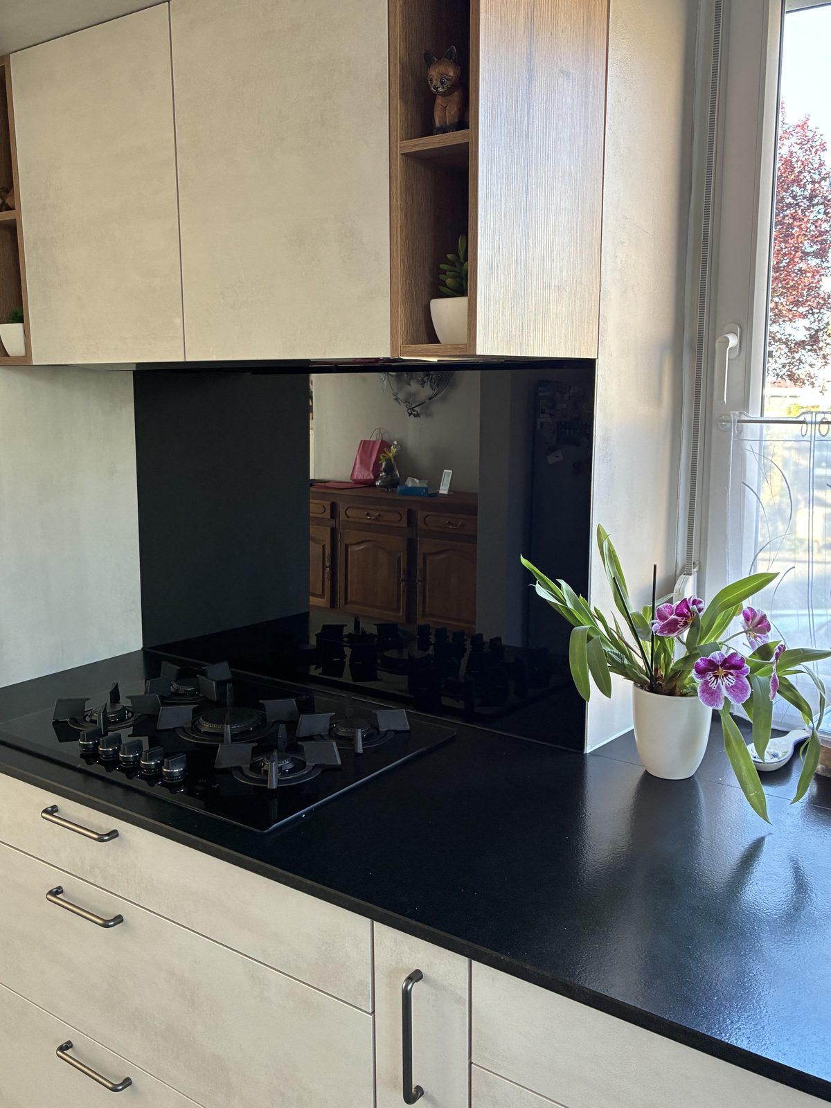 Crédence en verre laqué noir derrière une plaque de cuisson — réalisation CM Déco